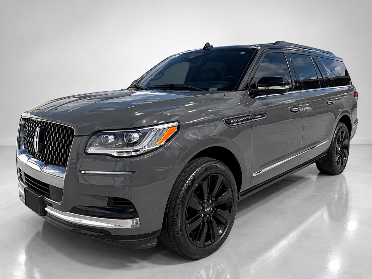 Gray Lincoln Navigator luxury SUV shown from the front three-quarter angle in a photo studio, with mirror-like reflections in its freshly corrected paint
